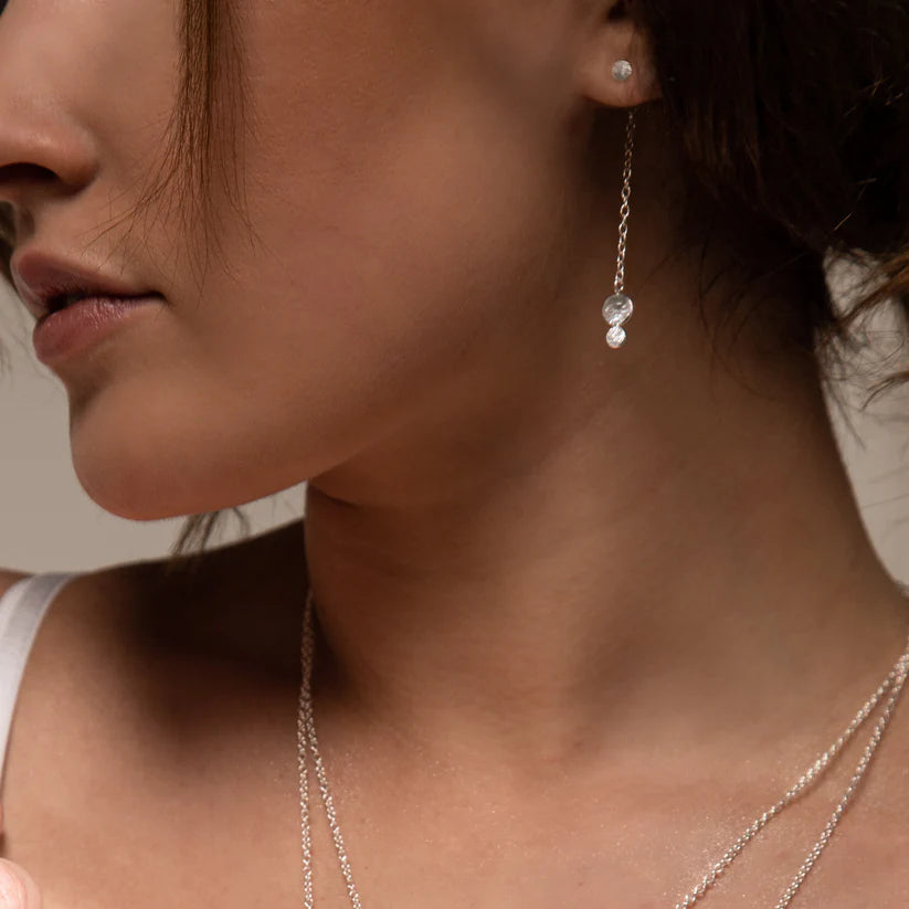 Delicate silver chain earrings featuring two small, clear gemstone accents.