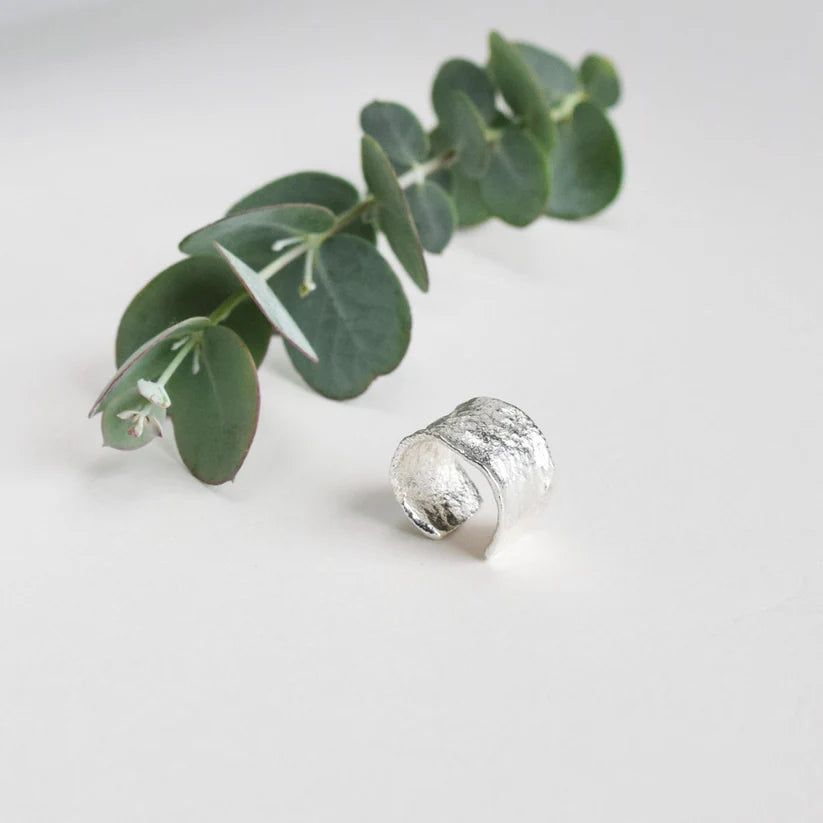 Silver textured band ring; open, slightly curved design.