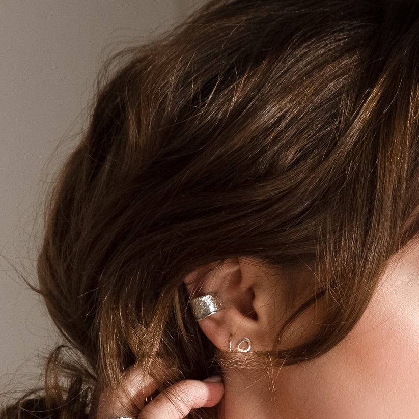 Silver ear cuff and small silver heart stud earrings.
