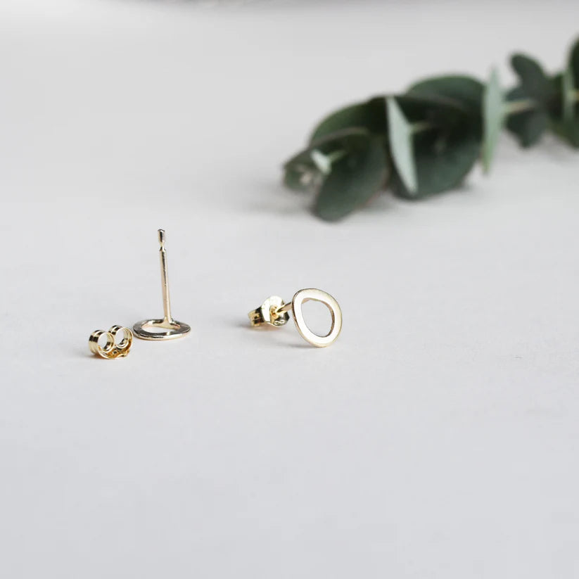 Gold stud earrings; each earring features a small, open, organic-shaped circle.