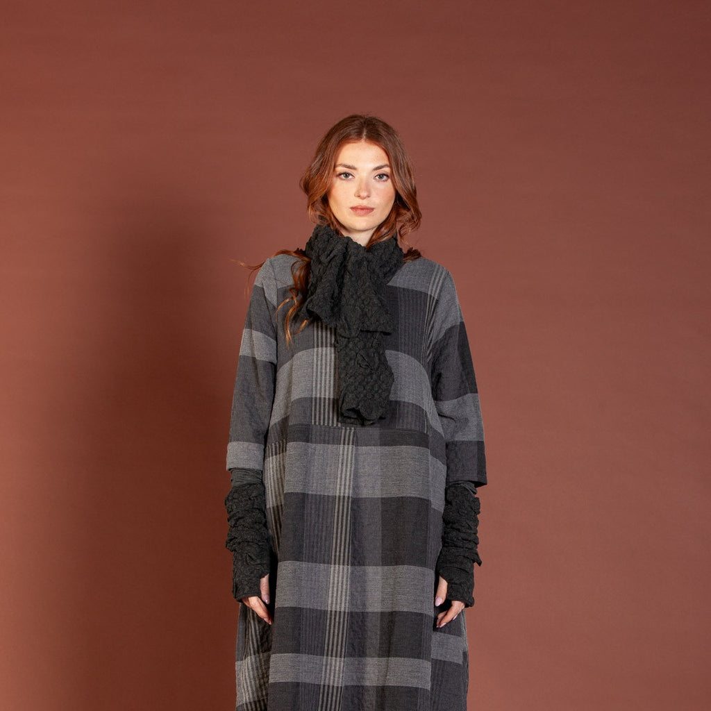 Woman wearing a long, plaid dress against a brown background