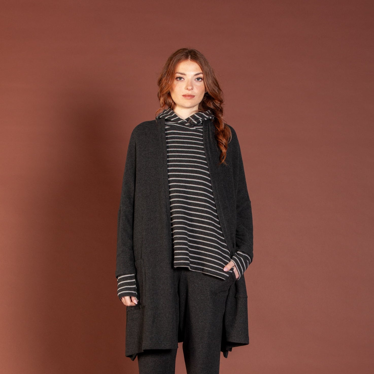 Woman wearing a black outfit with a striped shirt against a brown background