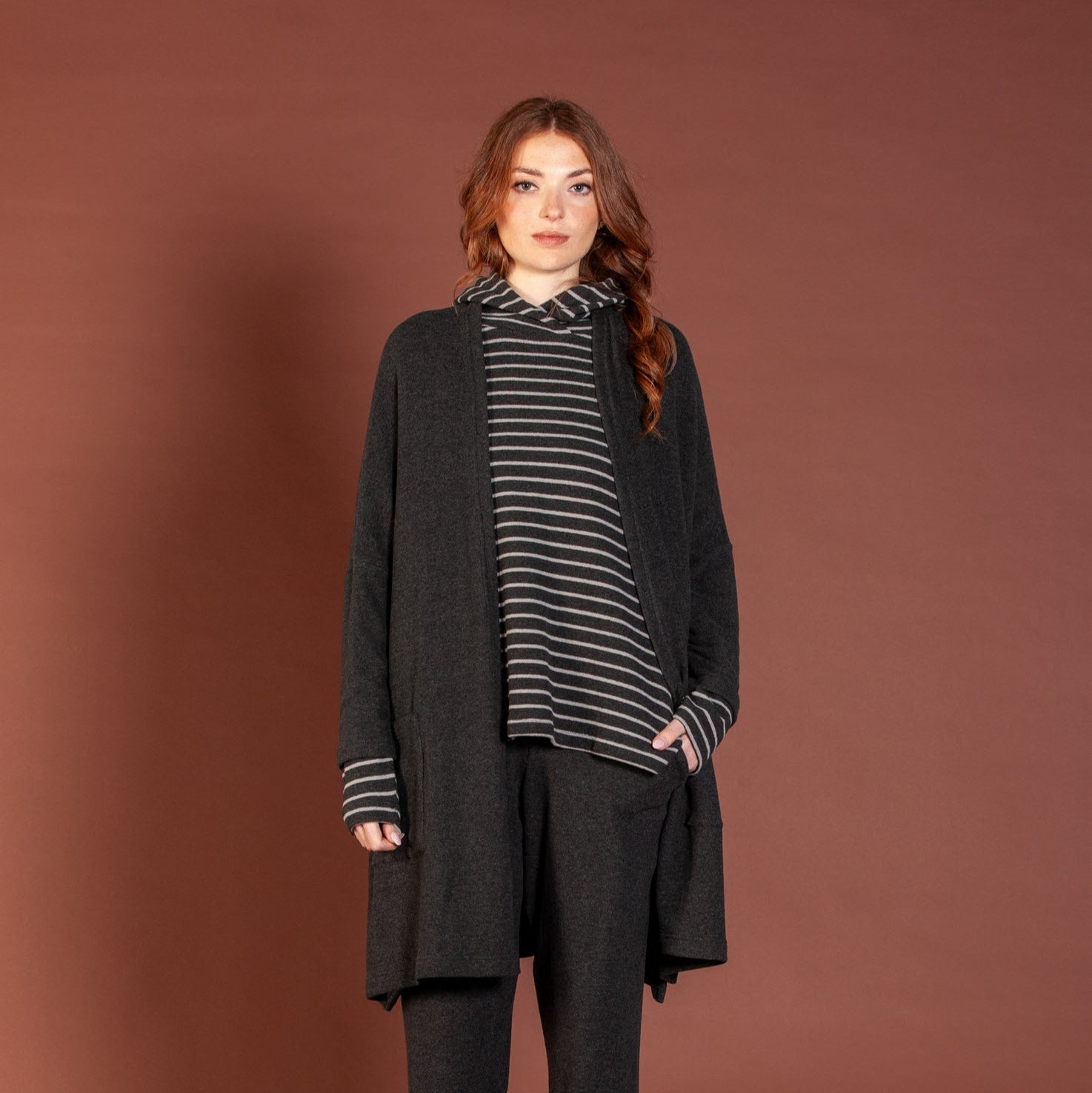 Woman wearing a black outfit with a striped shirt against a brown background