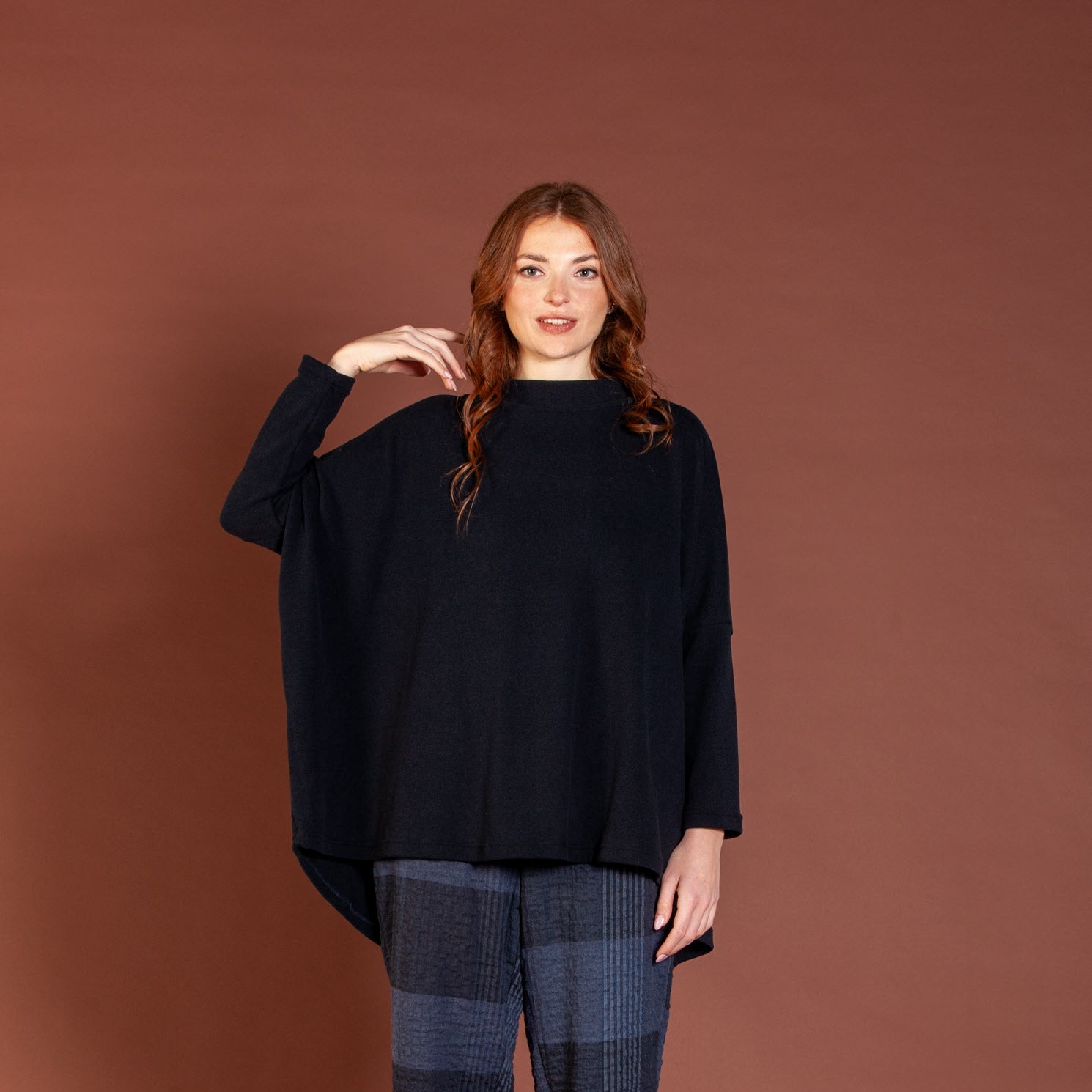 Woman wearing a black sweater and blue striped pants against a brown background