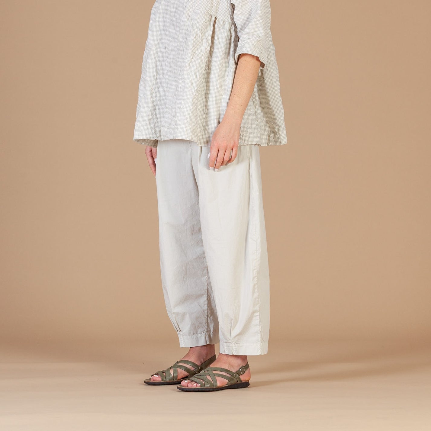 Woman wearing a light-colored outfit against a beige background