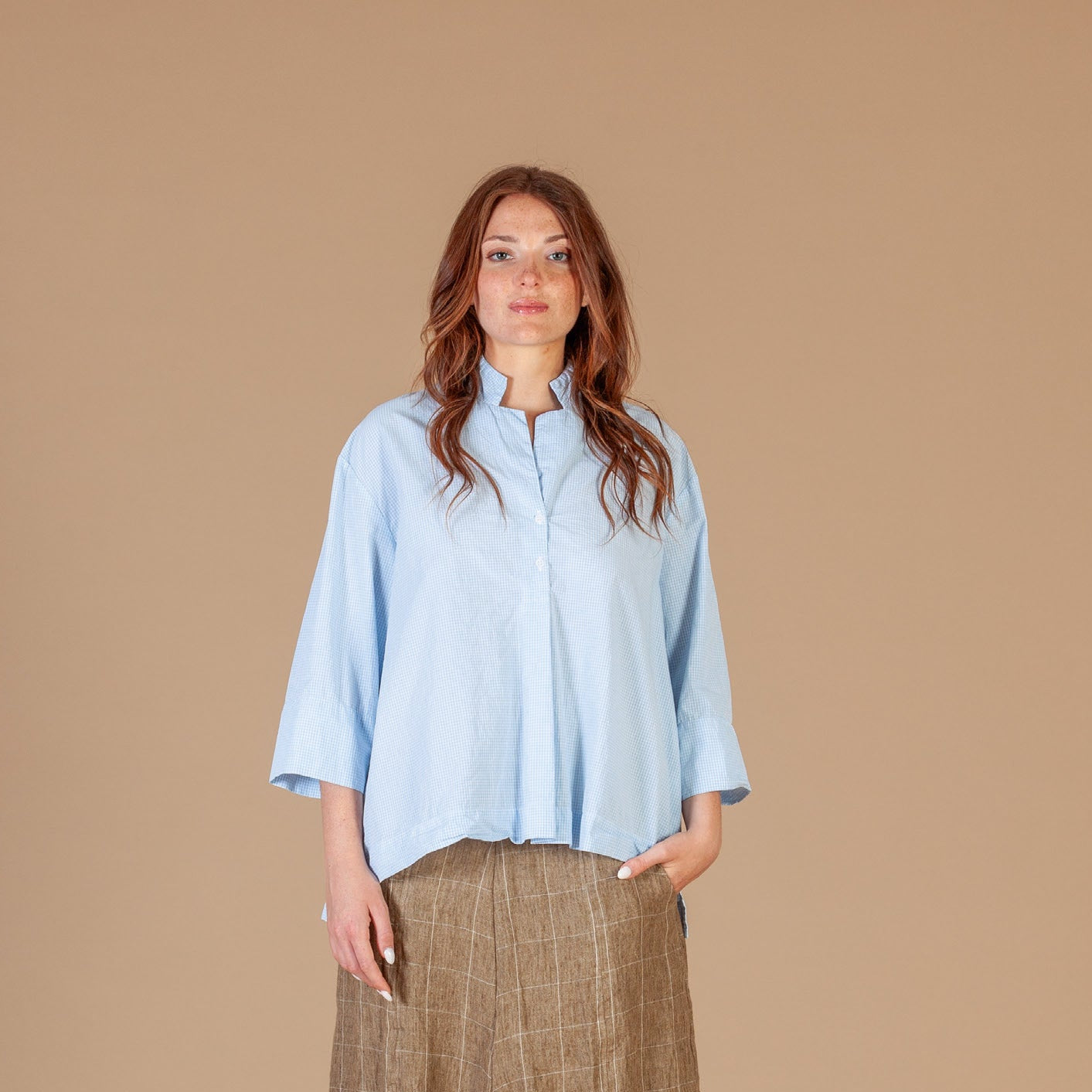 Women wearing a blue and cream check shirt. Loose fit with stand up collar. 