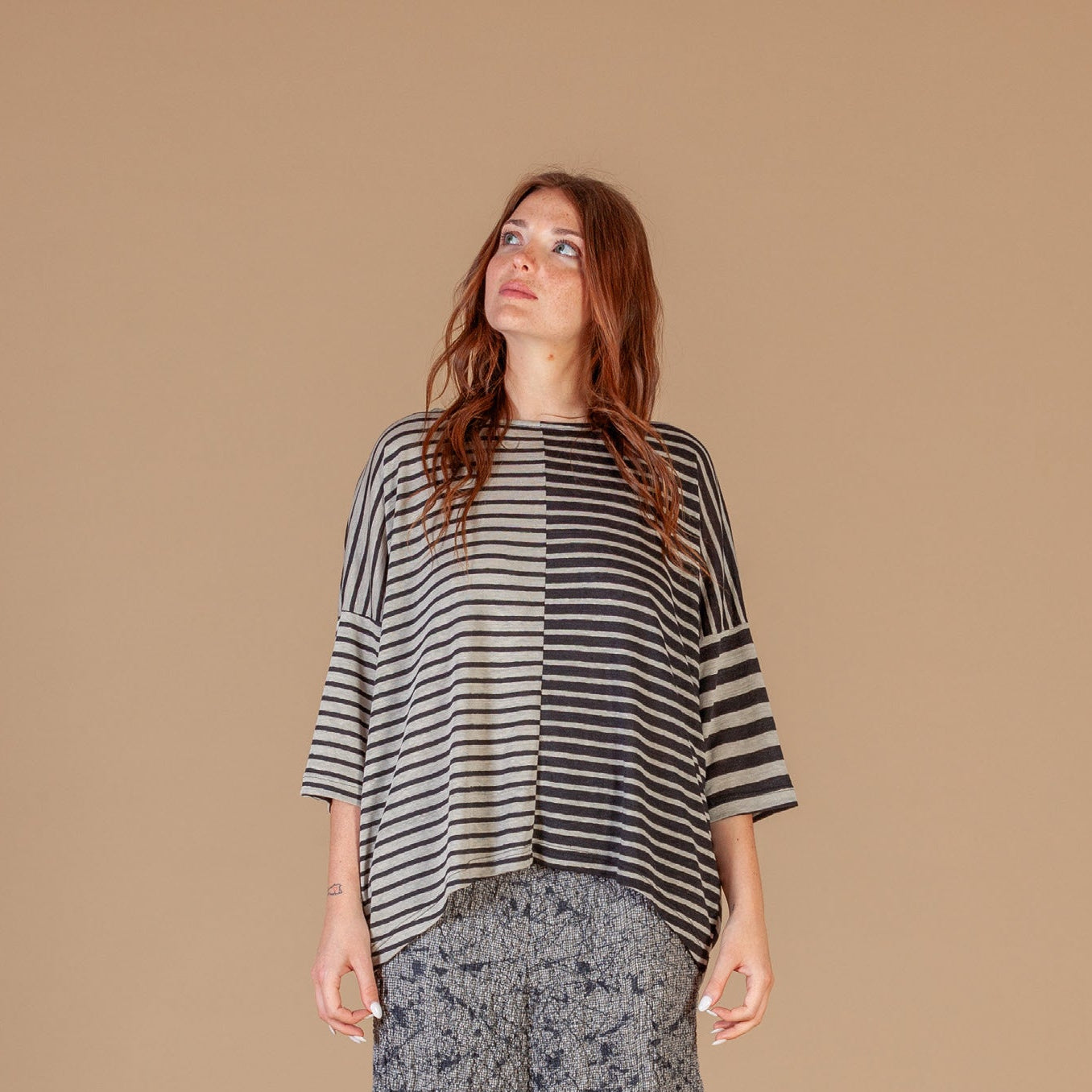 Woman wearing a striped top and patterned pants against a beige background