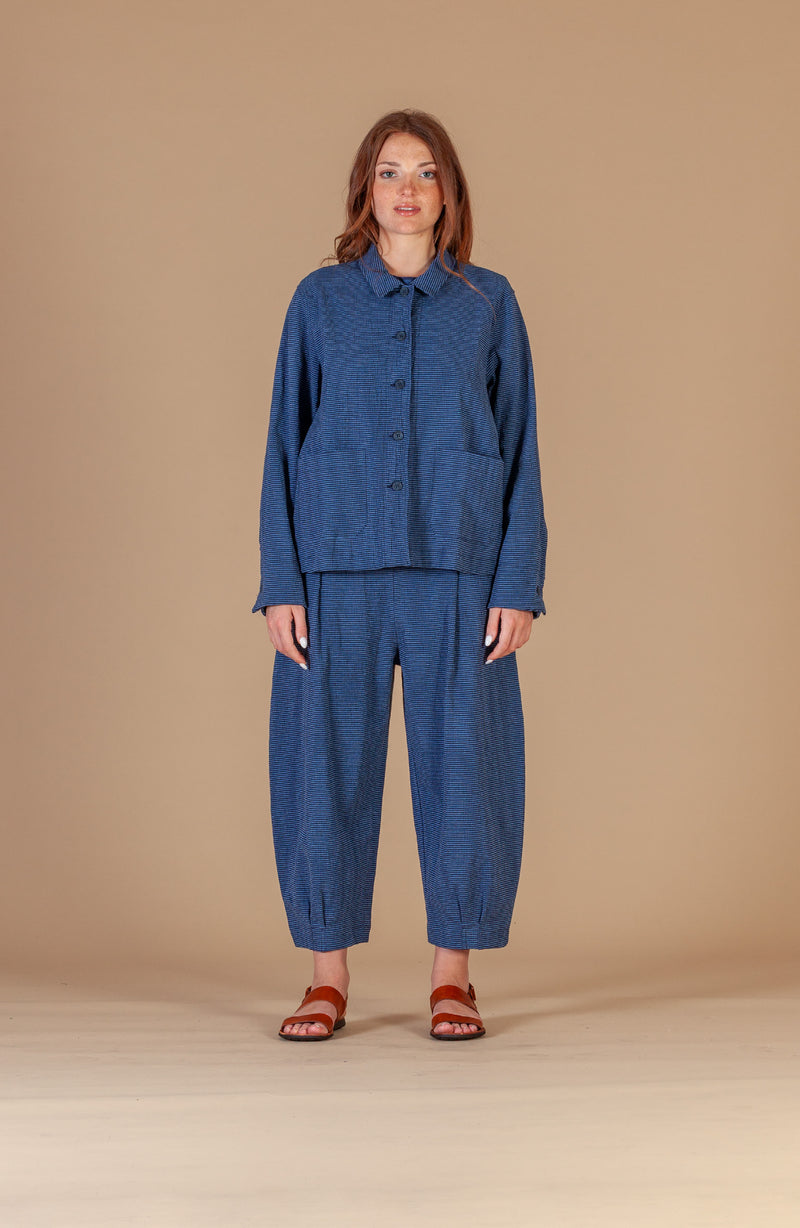 Woman wearing a blue outfit against a beige background