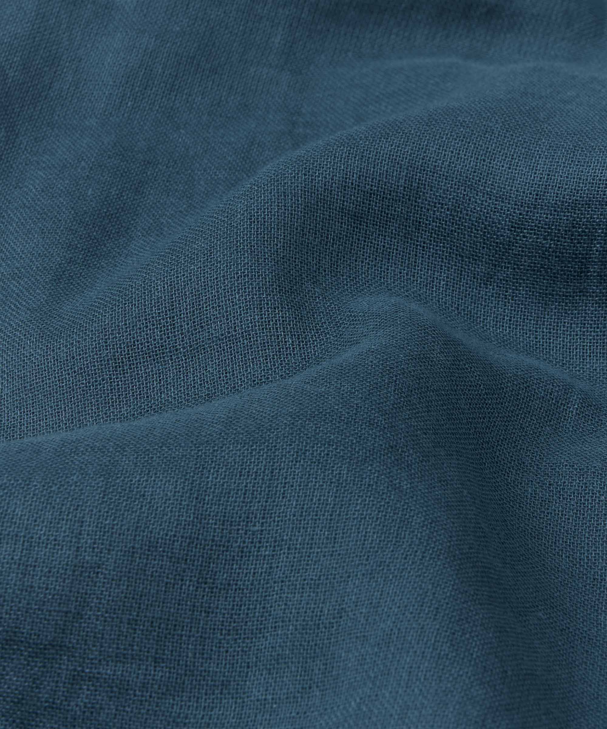 Close-up of teal fabric with a textured weave, showing soft folds and wrinkles.