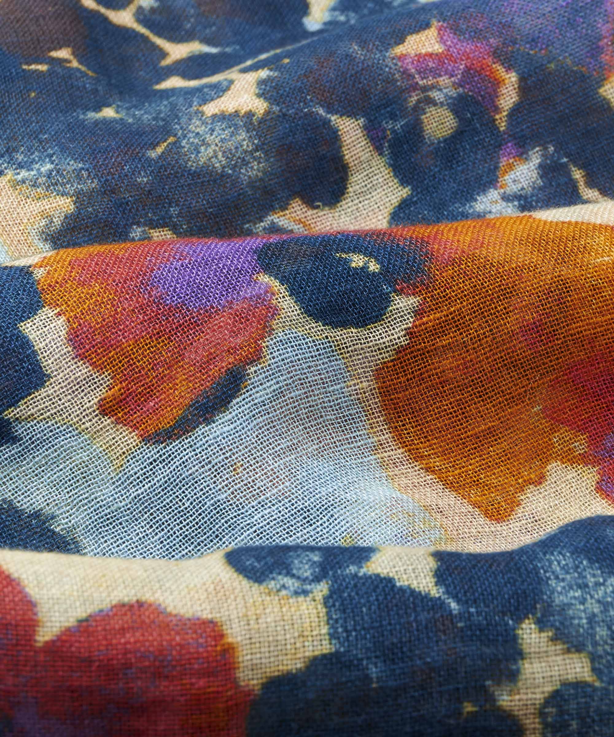 Close-up of textured fabric with an abstract floral print in shades of blue, orange, red, and purple.