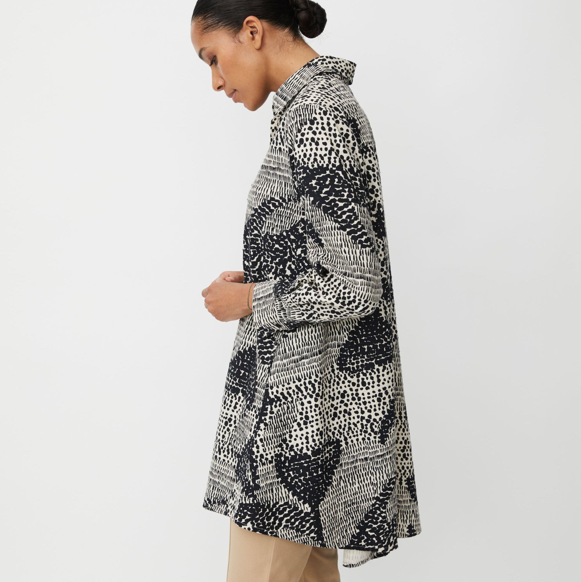 Woman wearing a black and white patterned tunic on a white background