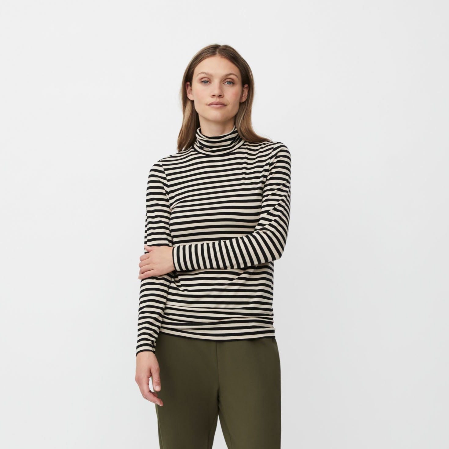 Woman wearing a striped top and green pants on a white background