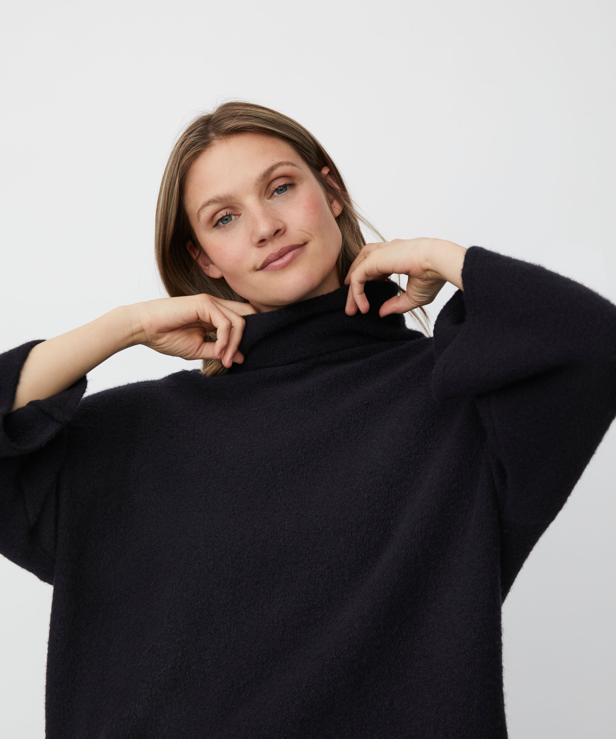 Woman wearing a black sweater against a plain background