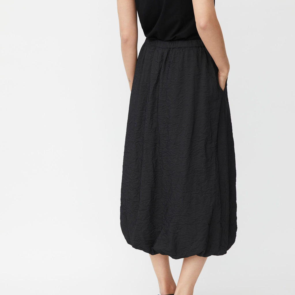 Black midi skirt with a textured, crinkled fabric and a balloon hem.  Elastic waistband.  Side pockets.