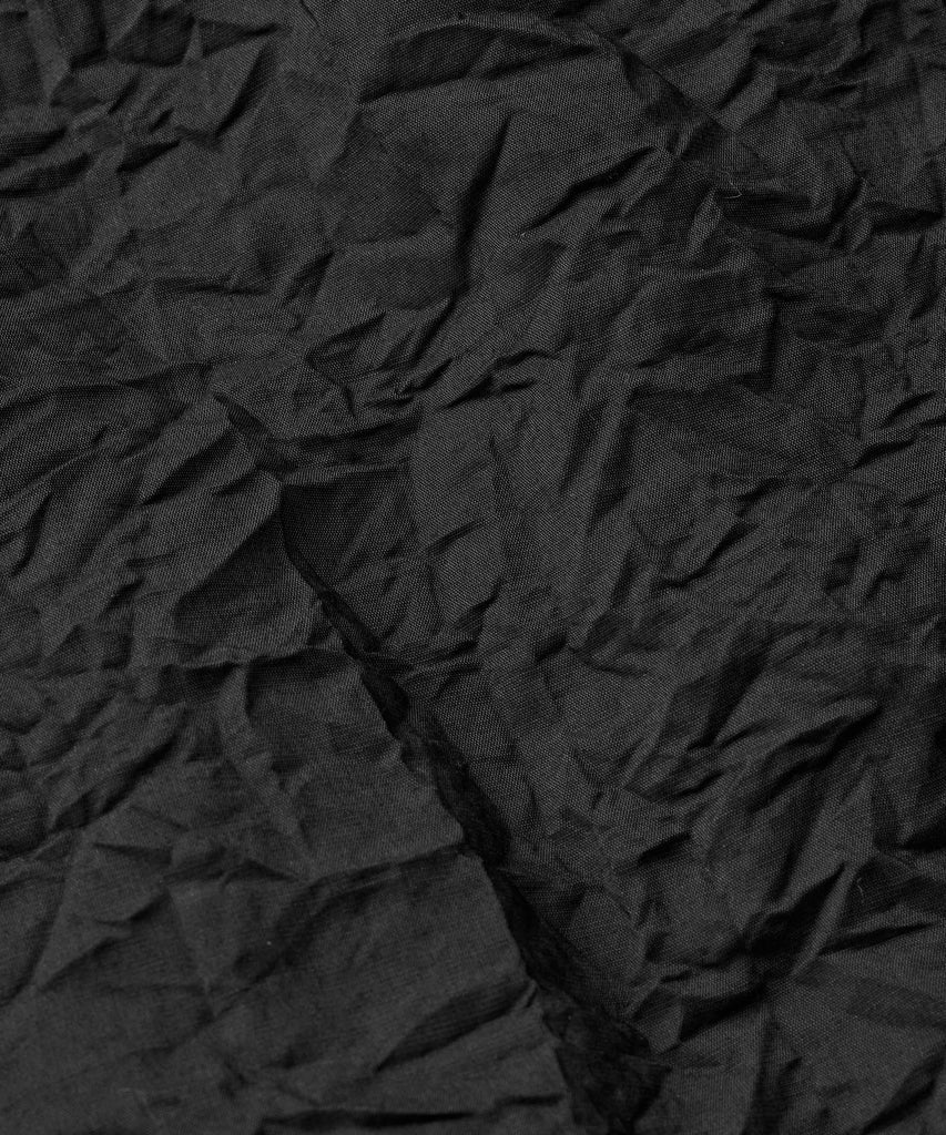 Close-up of dark gray, textured fabric with deep wrinkles and folds.