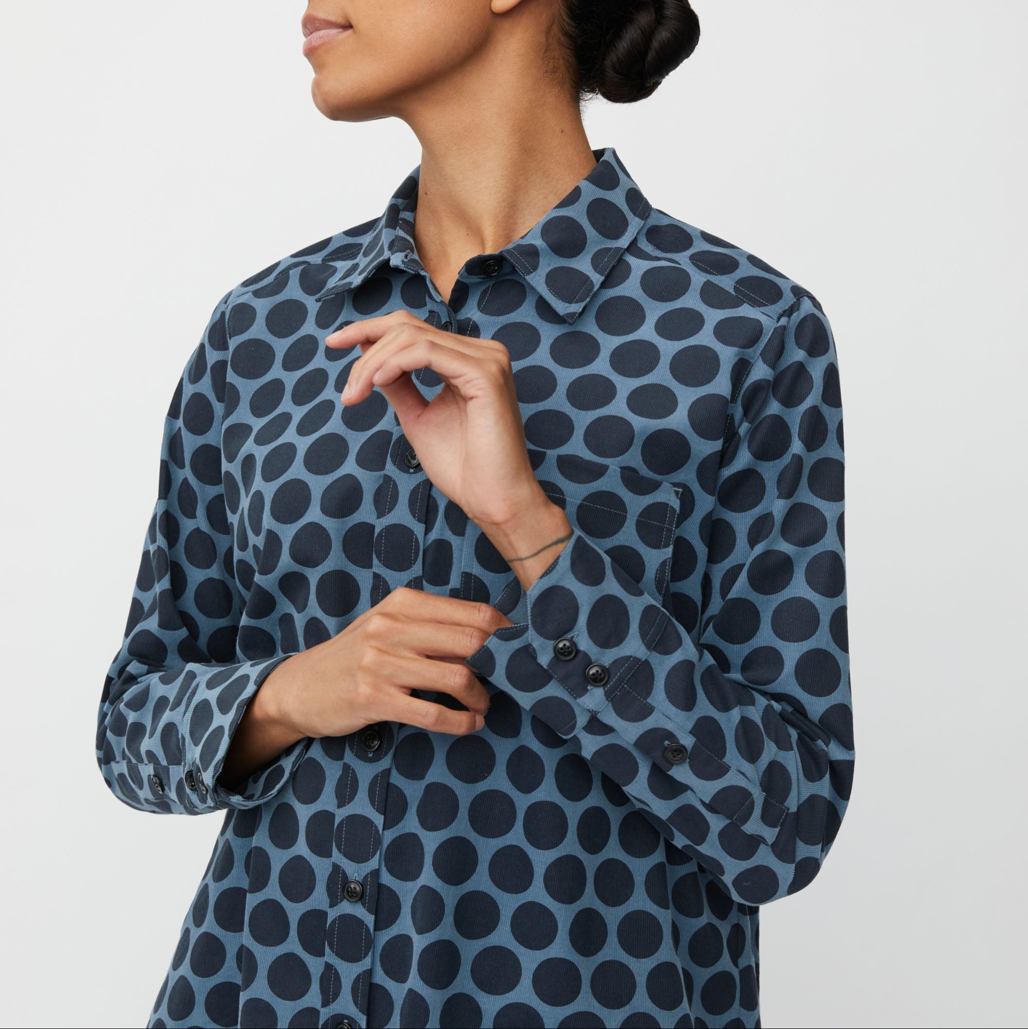 Woman wearing a blue polka dot shirt against a white background