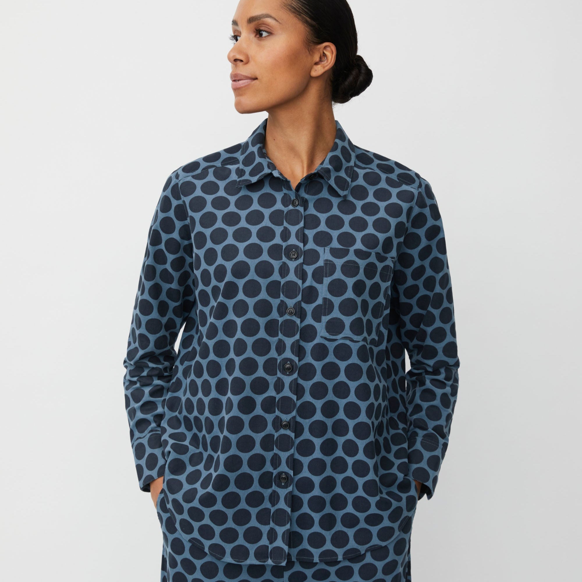 Woman wearing a blue polka dot shirt and pants on a white background