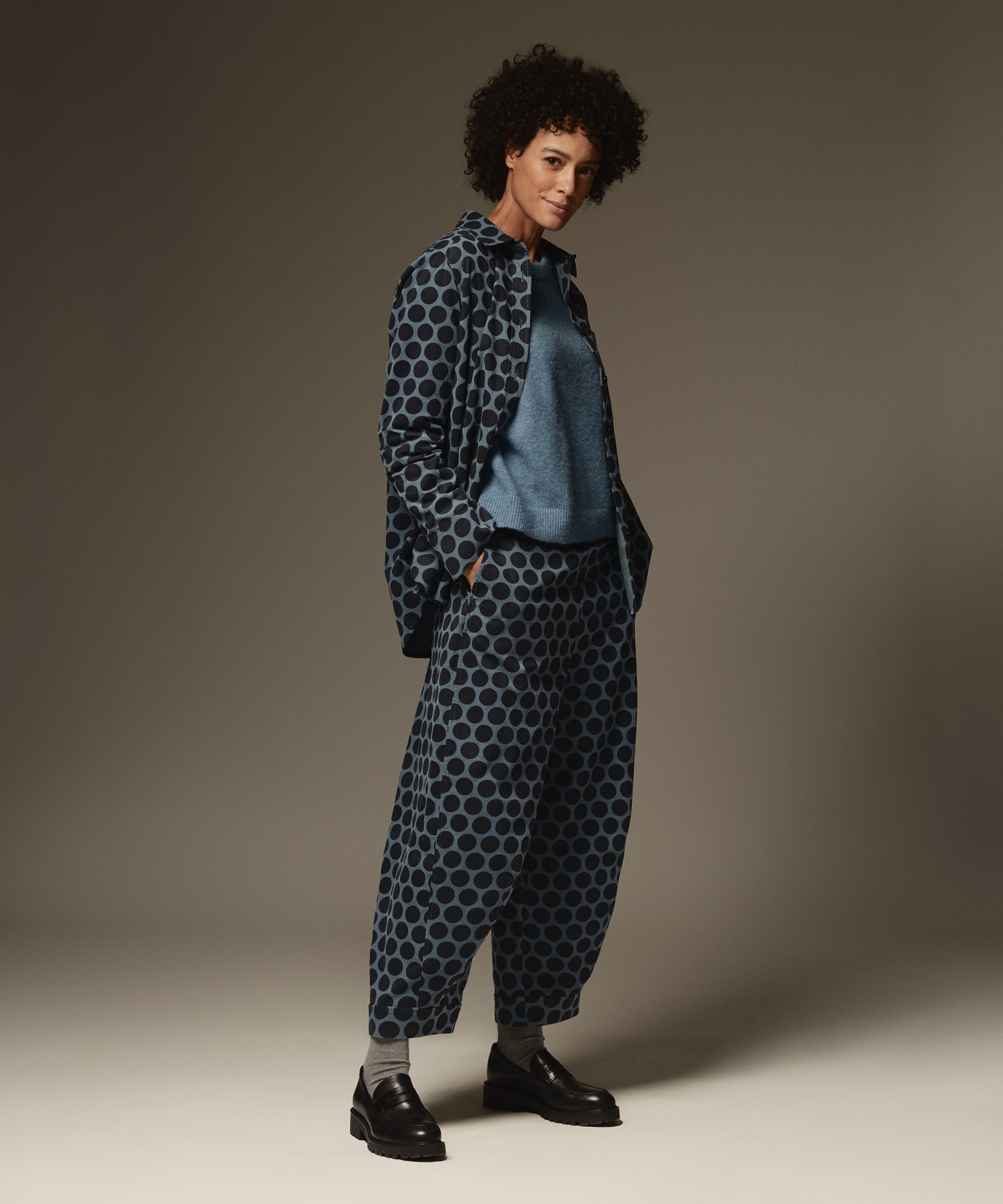 Person wearing a blue patterned outfit against a plain background