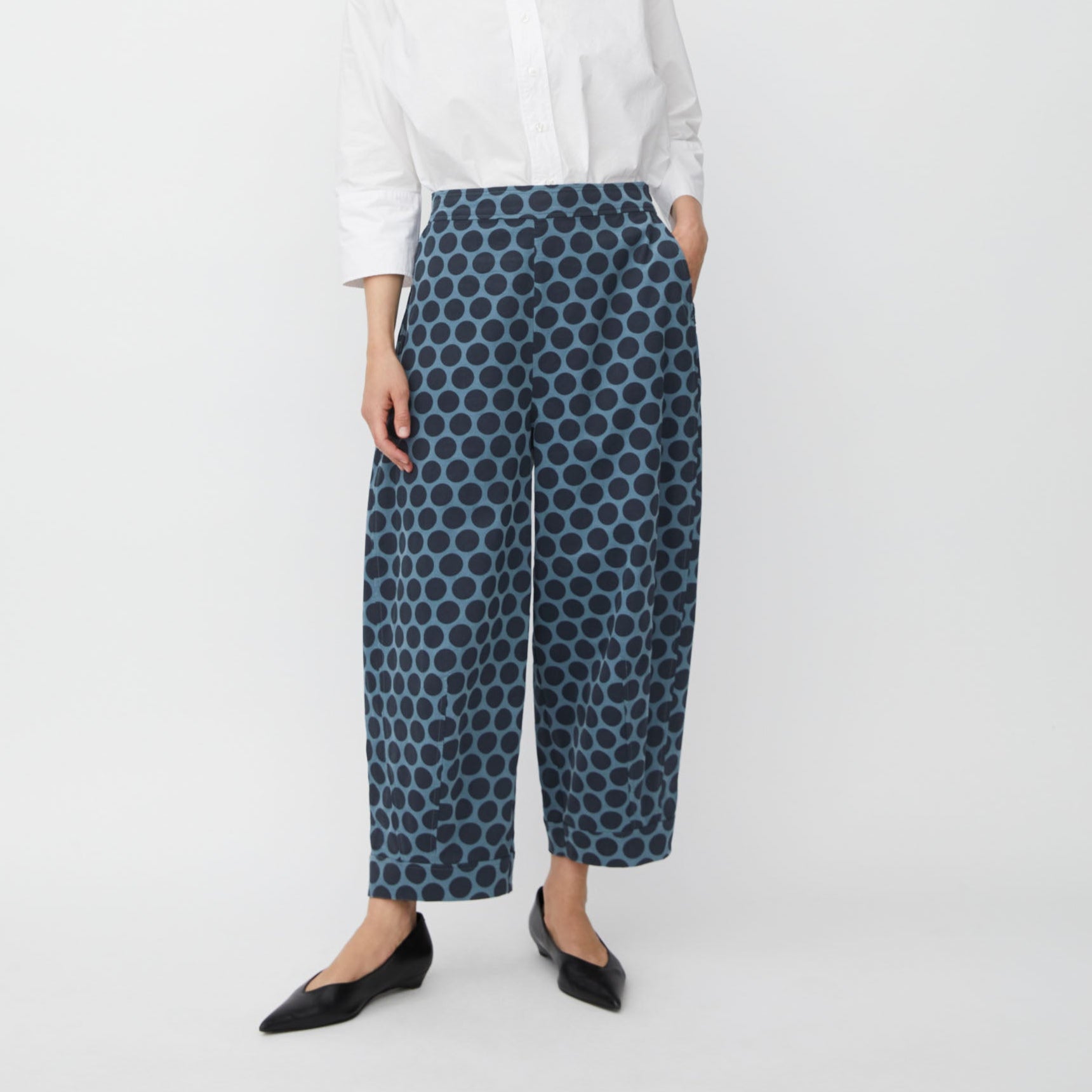 Woman wearing a white shirt and blue patterned pants on a white background