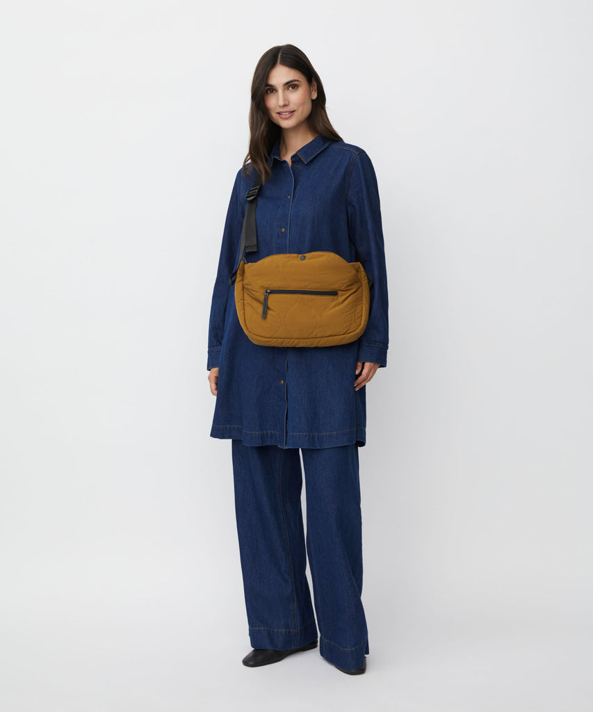Mustard-colored quilted crossbody bag with a black strap and zippered pocket.