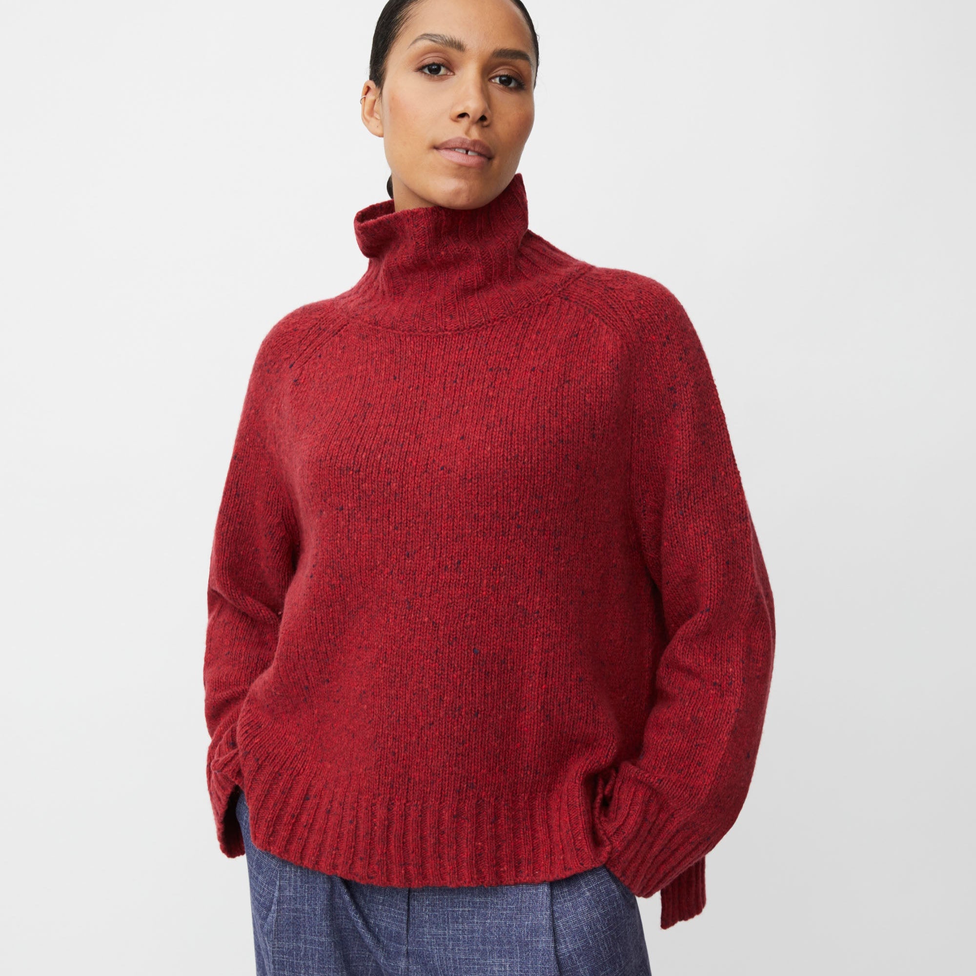 Woman wearing a red turtleneck sweater against a white background