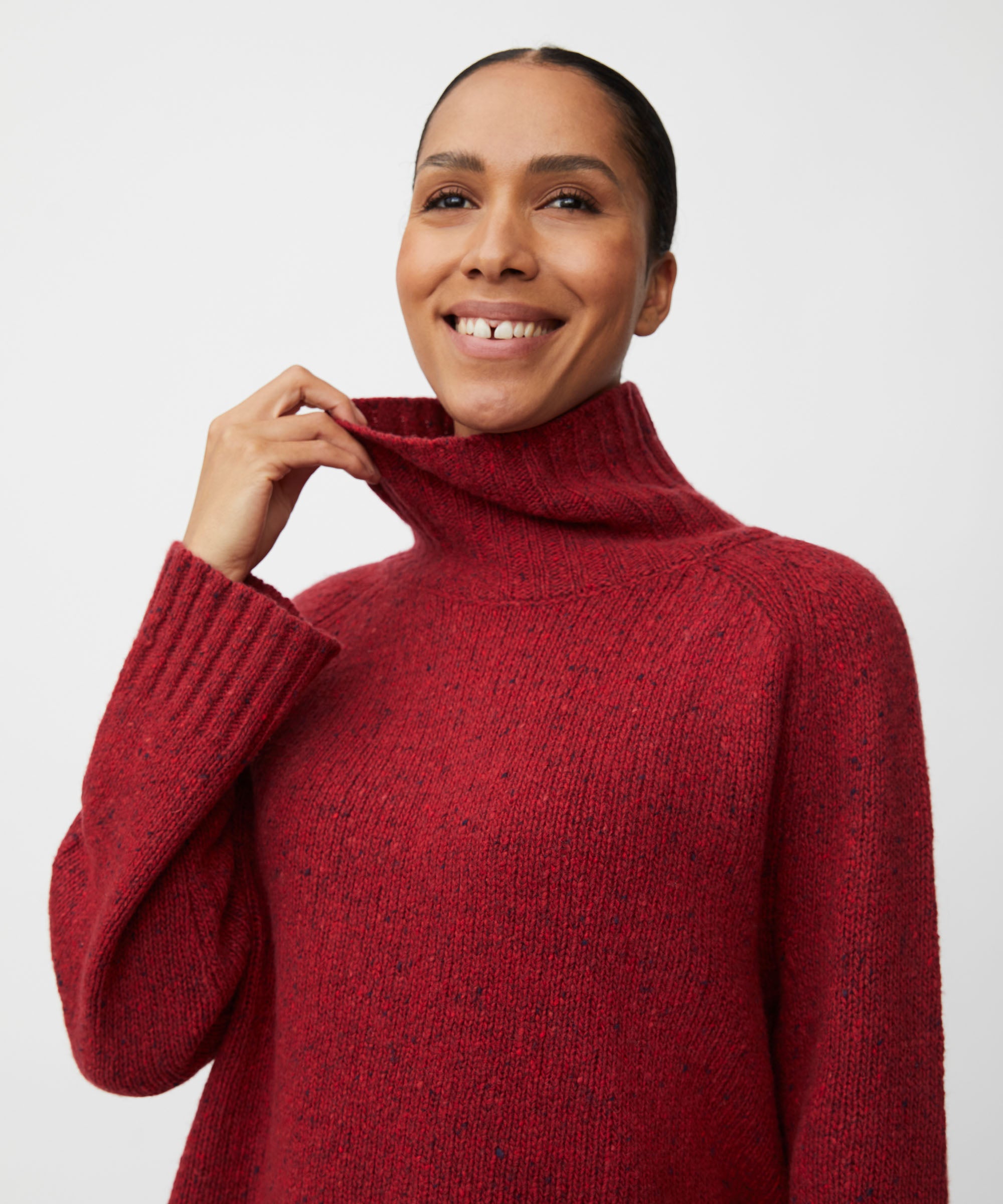 Woman wearing a red turtleneck sweater against a white background