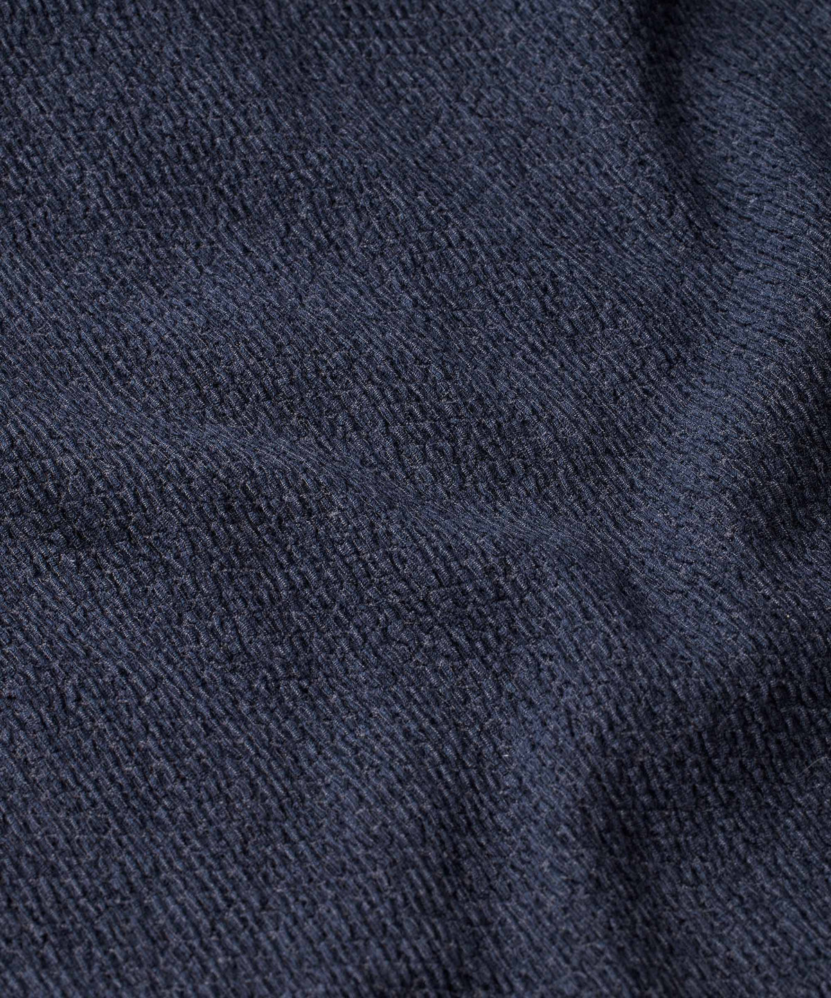 A close-up of dark navy blue textured fabric with a fine woven or knit pattern and soft folds.