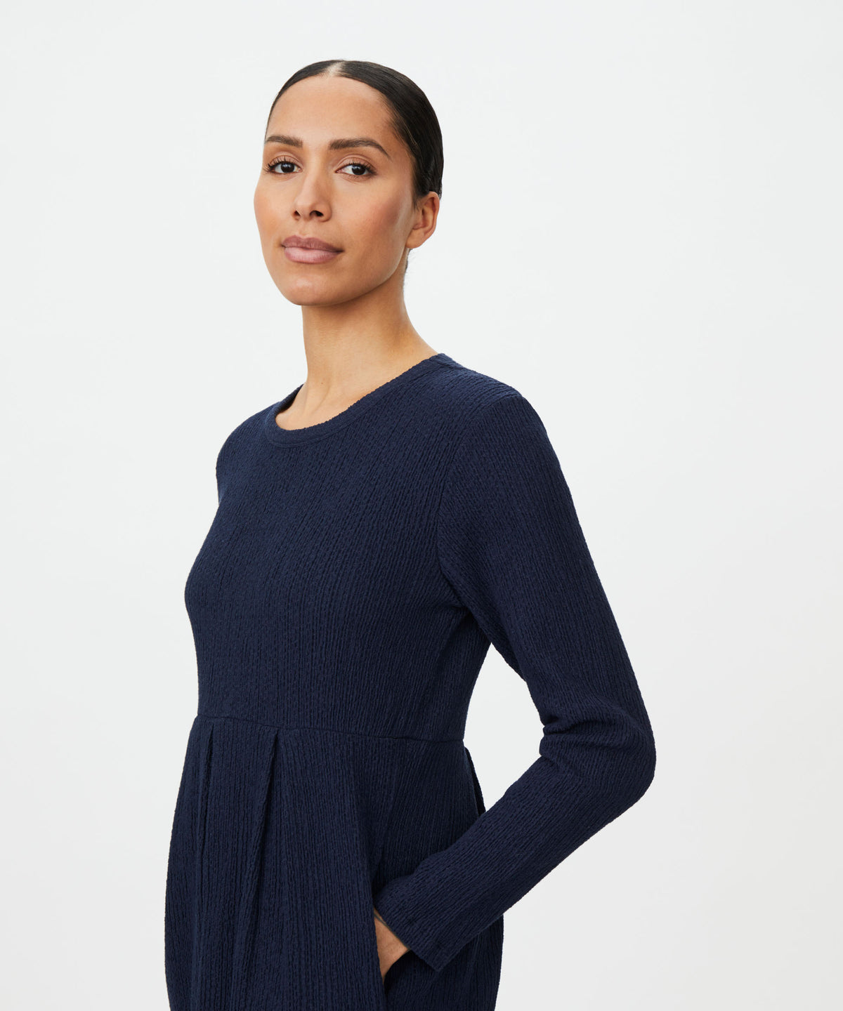 A woman modeling a dark navy blue long-sleeve knit dress against a plain white studio background.