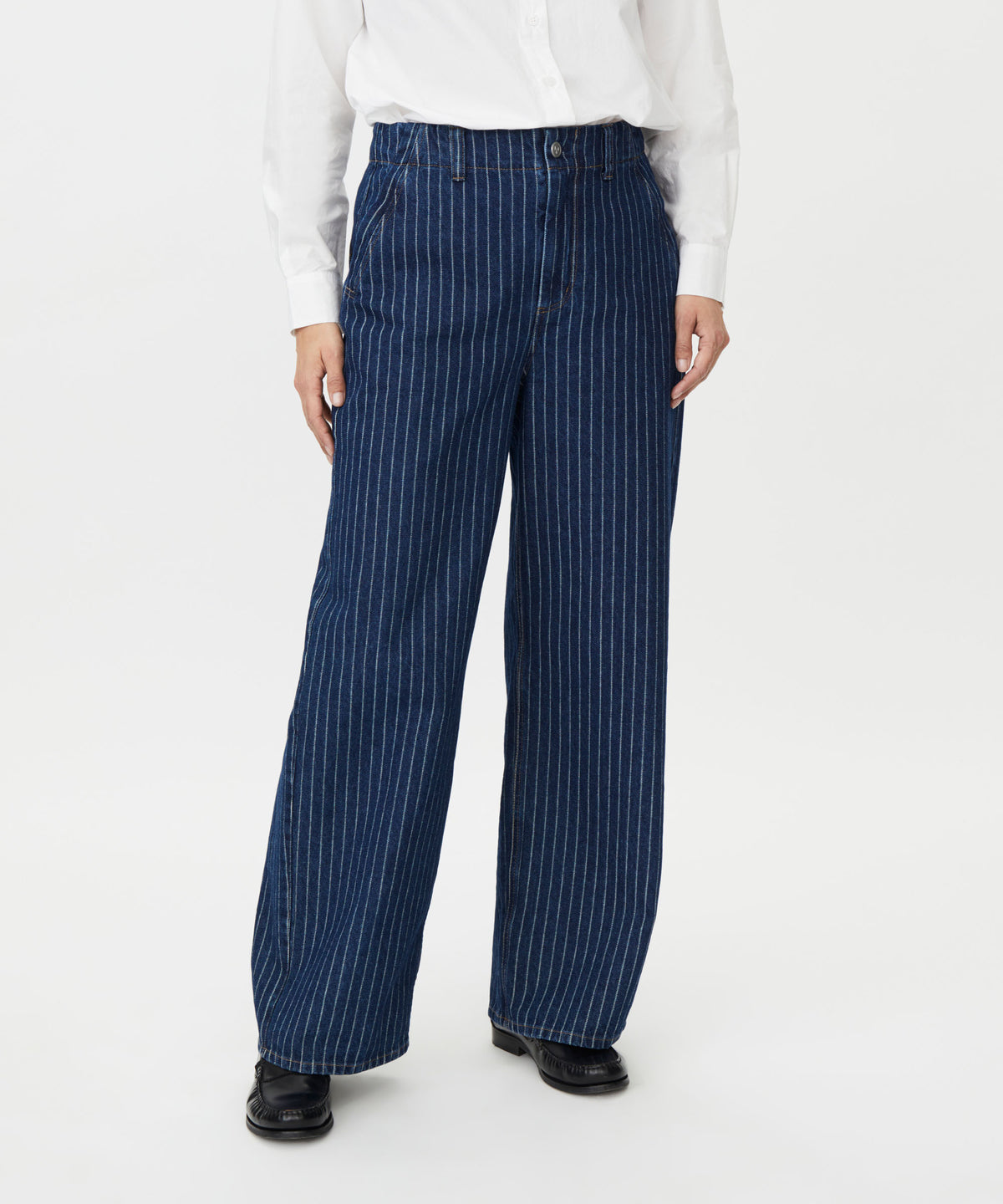 A person wearing dark blue wide-leg pinstripe trousers with a white button-up shirt and black shoes, shown from the waist down against a plain light gray studio background.