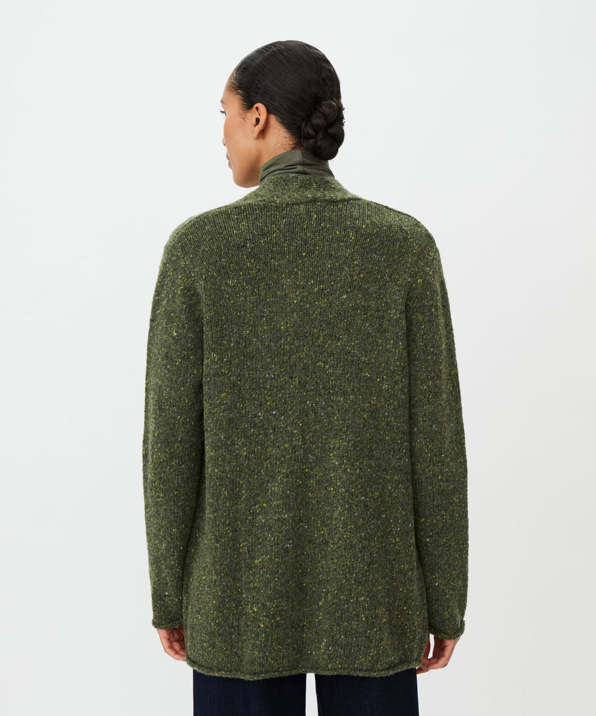 A person shown from the back wearing a textured olive green knit sweater with a high mock neck, photographed against a plain light gray studio background.