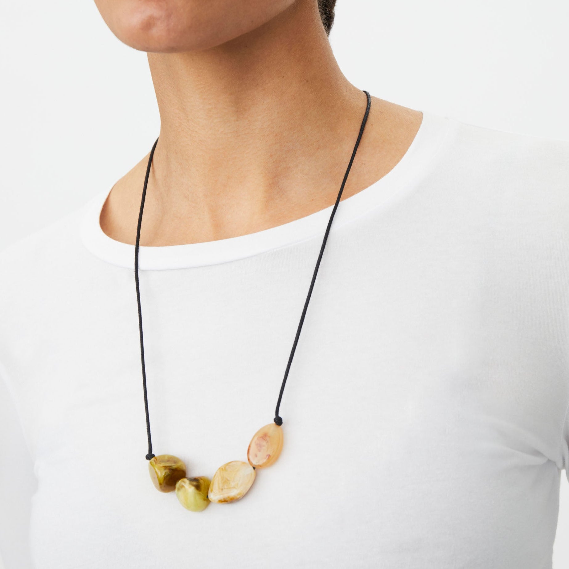 Woman wearing a necklace with stone pendants on a plain background