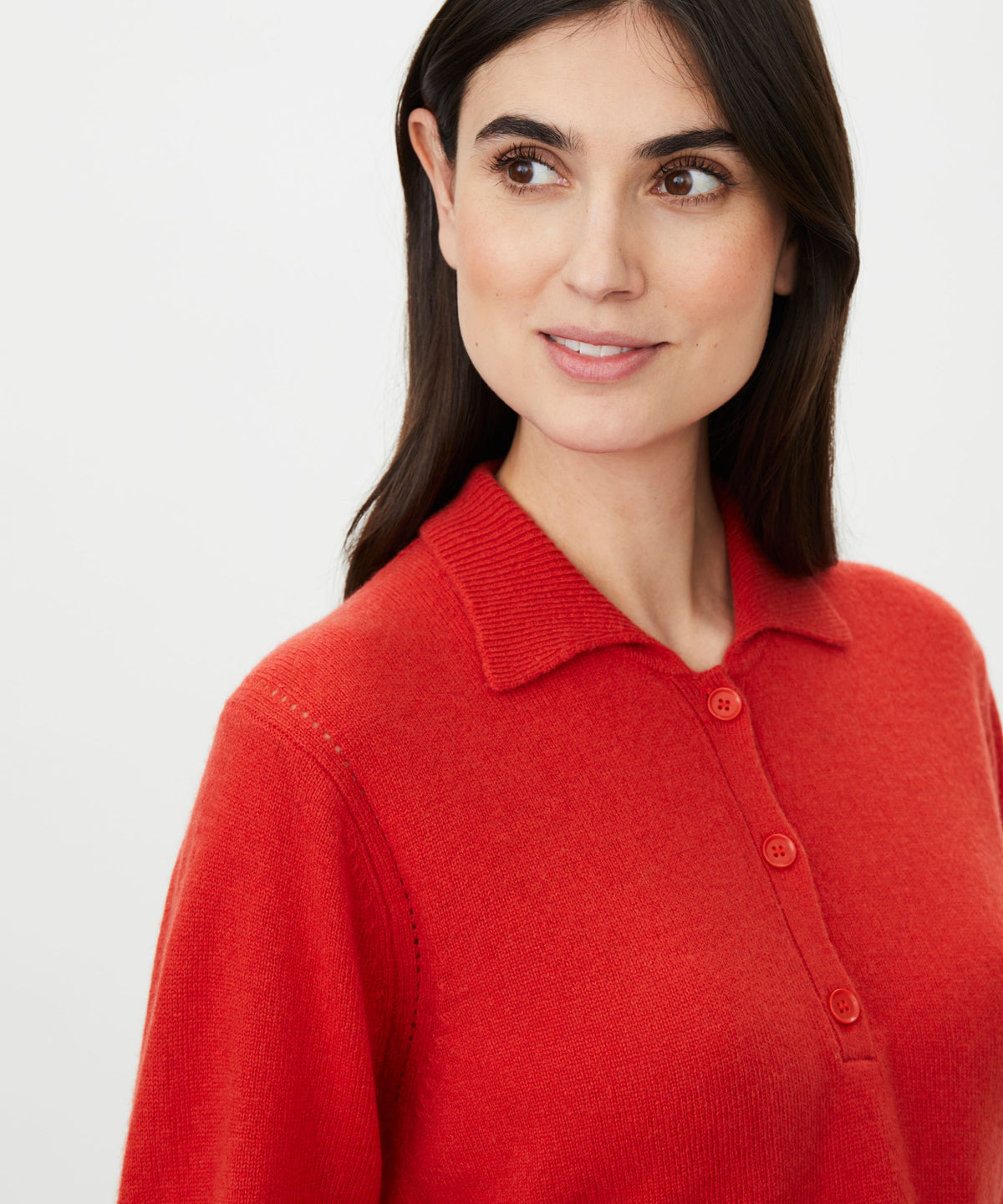 A close-up of a woman wearing a bright red knit polo sweater against a clean white background.