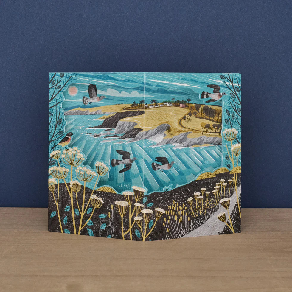 Greeting card with a landscape design featuring birds, fields, and mountains on a blue background.