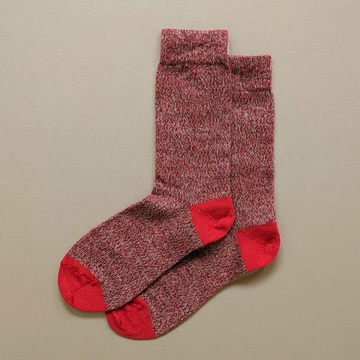 Pair of red and white speckled crew socks with red heels and toes.
