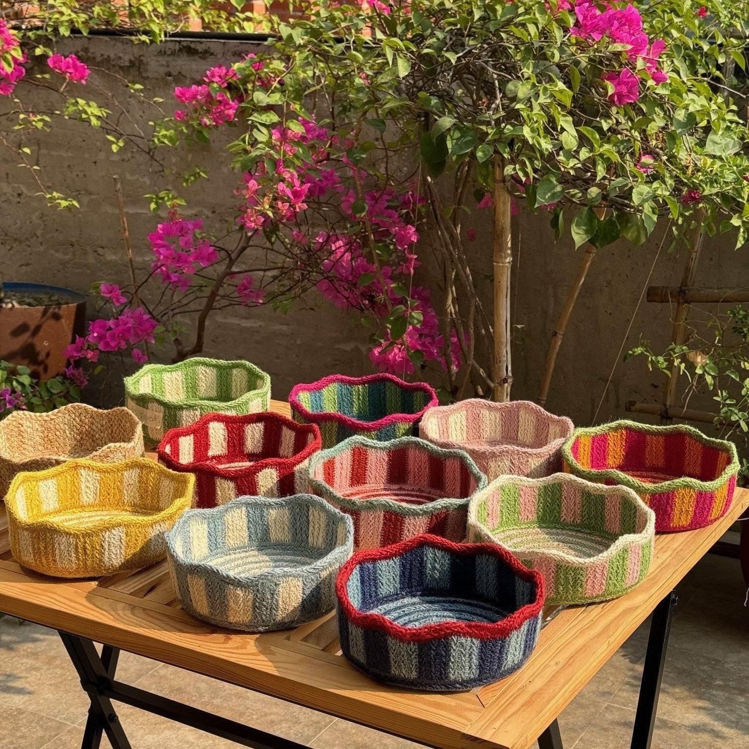 Collection of small, crocheted baskets in various colorful striped patterns. Each basket has a scalloped edge.