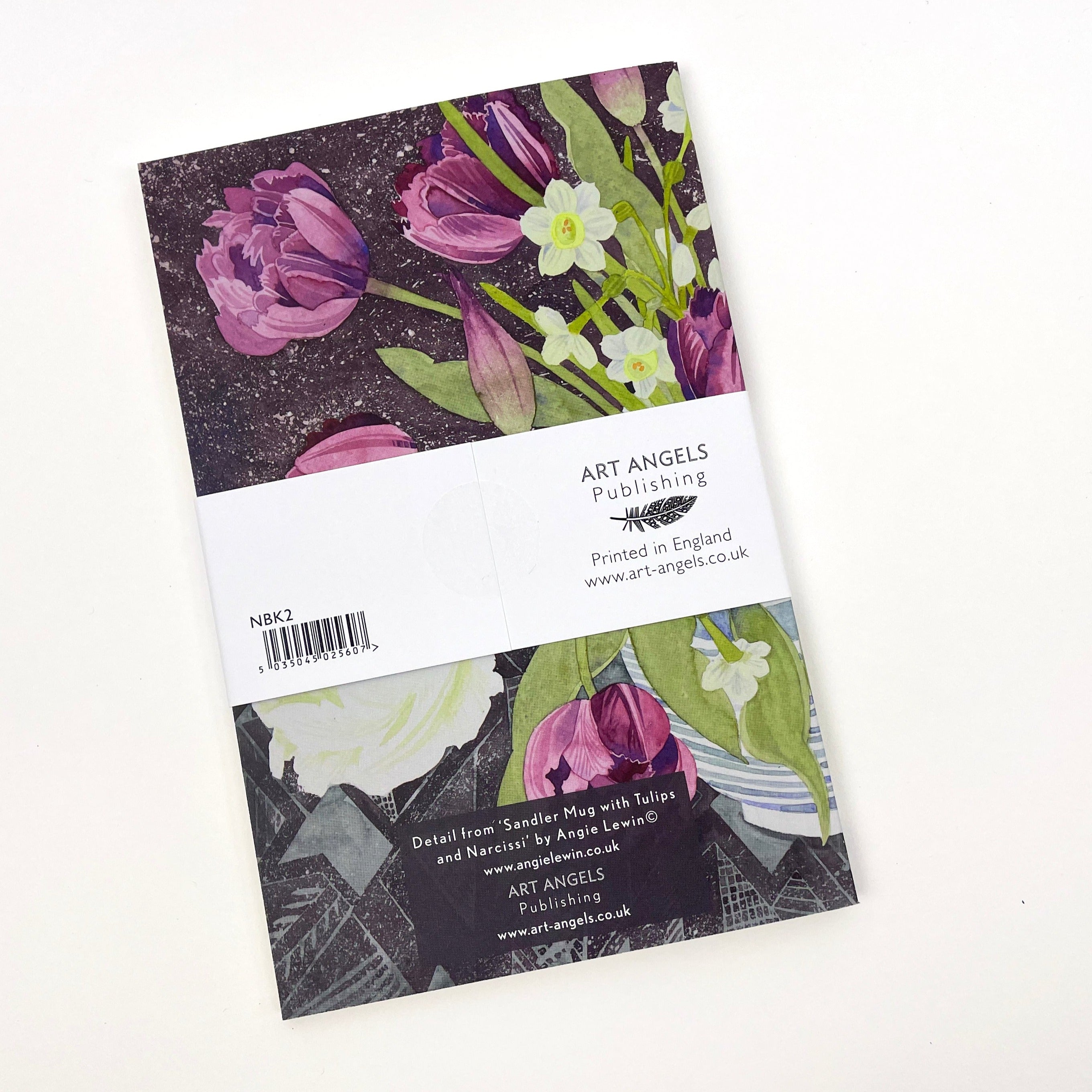 Notebook featuring watercolor painting of purple tulips and white daffodils on a dark background.