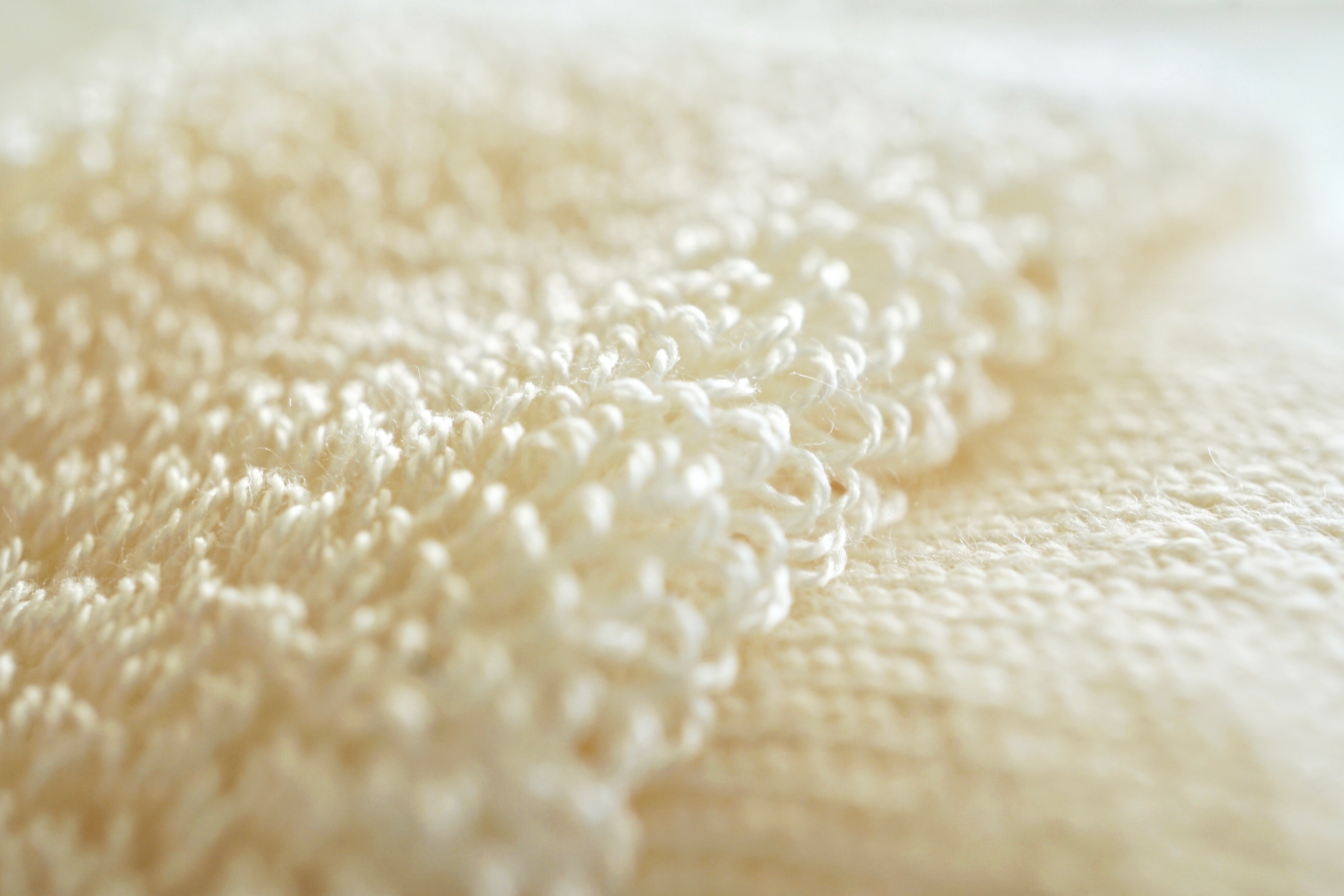 Close-up of creamy off-white fabric with a textured, looped surface.