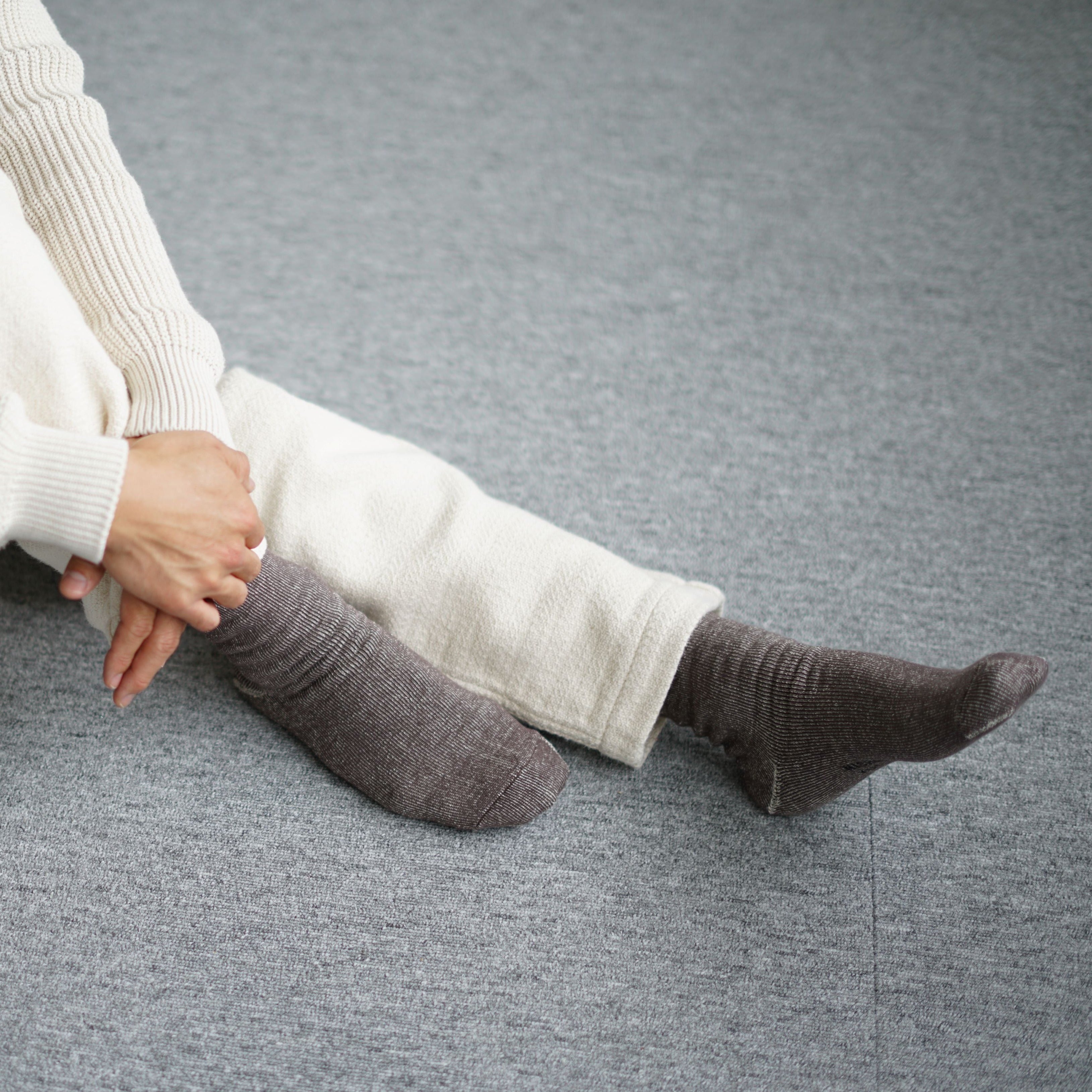 Pair of dark brown ribbed socks on a gray carpet.