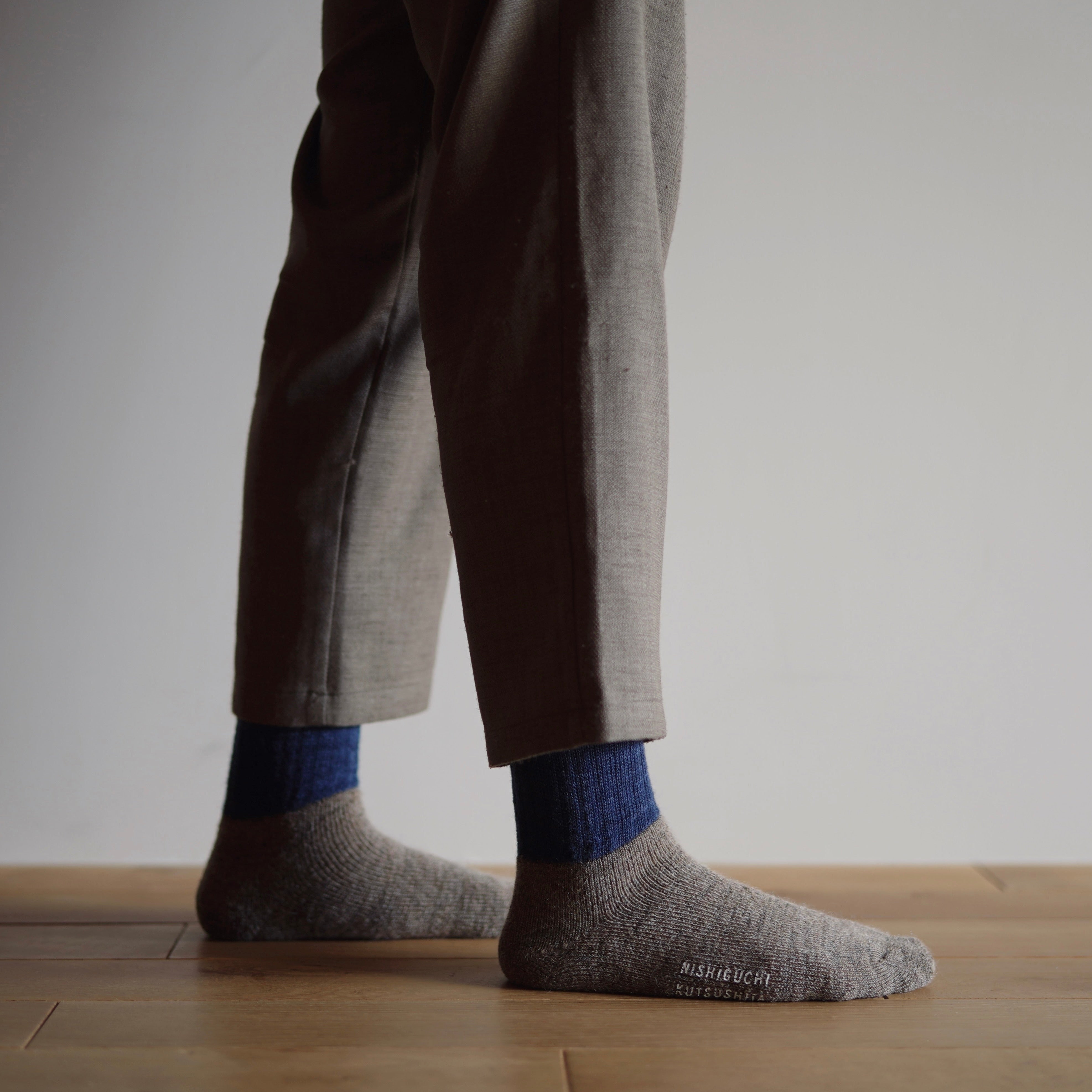 Pair of gray and navy blue wool socks.  The socks feature a ribbed texture and subtle branding on the sole.