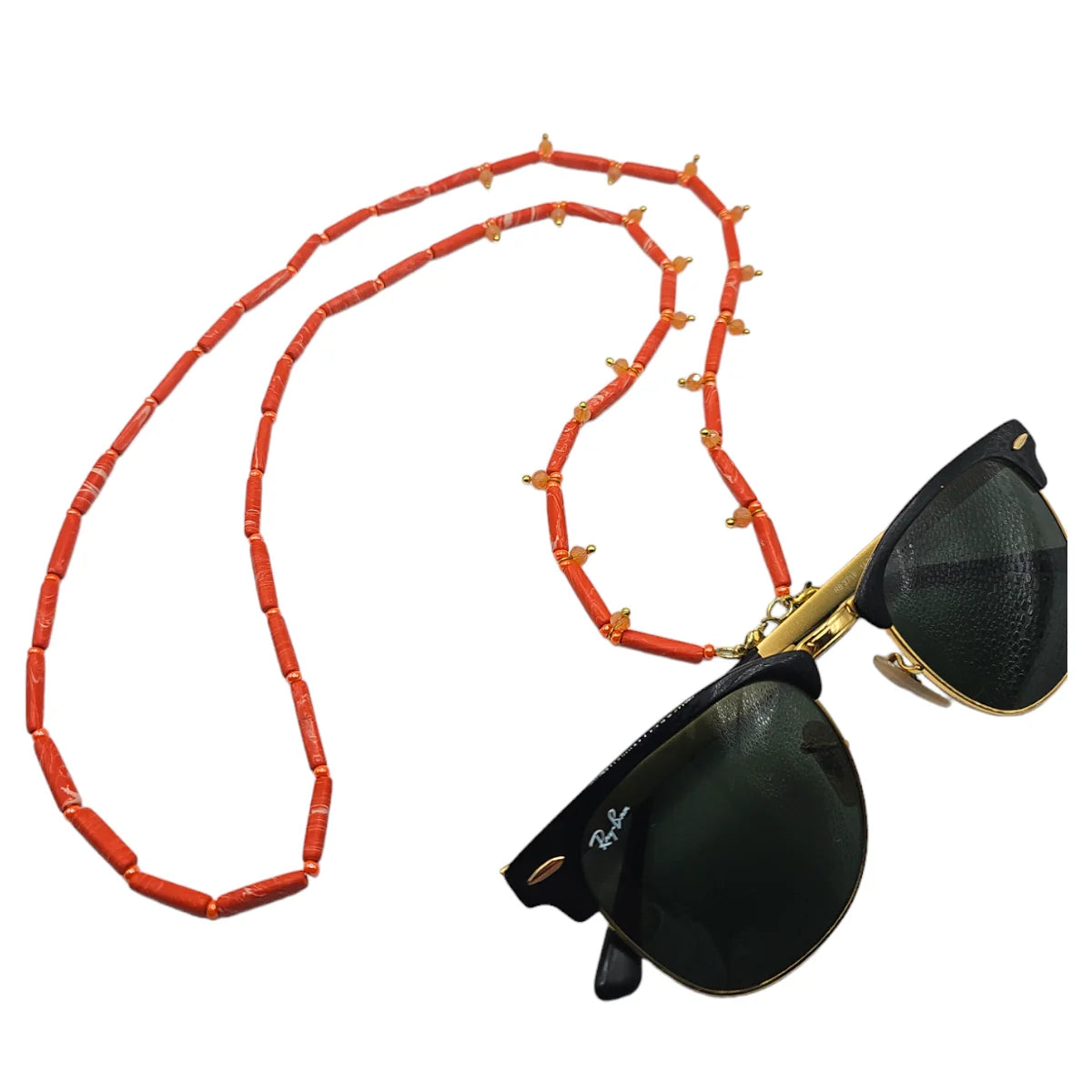 A pair of black Ray-Ban sunglasses with gold metal frames and a long orange beaded chain strap featuring small gold decorative accents, displayed on a solid white background.