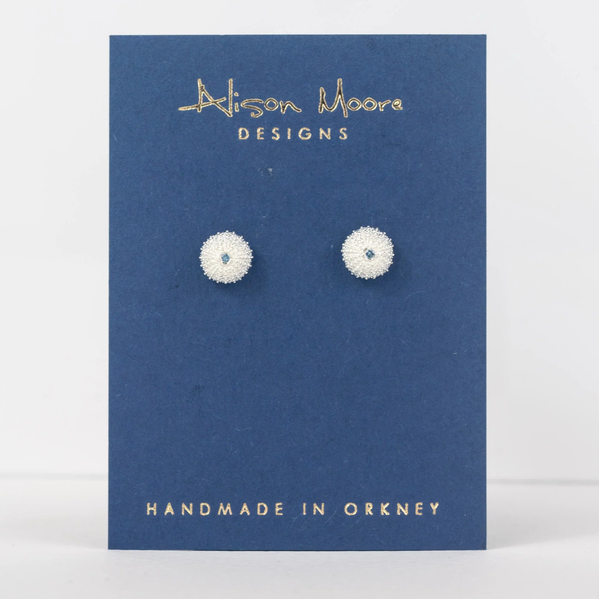 Pair of earrings on a blue card with 'Alison Moore Designs' branding