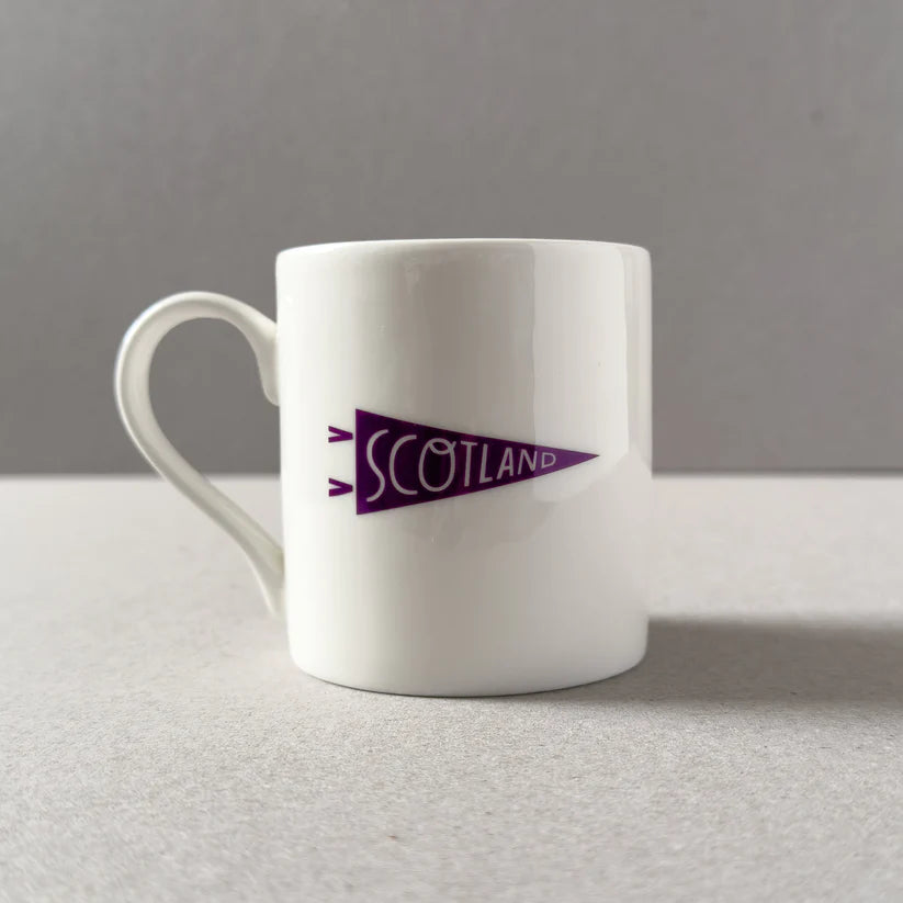 White mug with purple pennant design reading "Scotland".