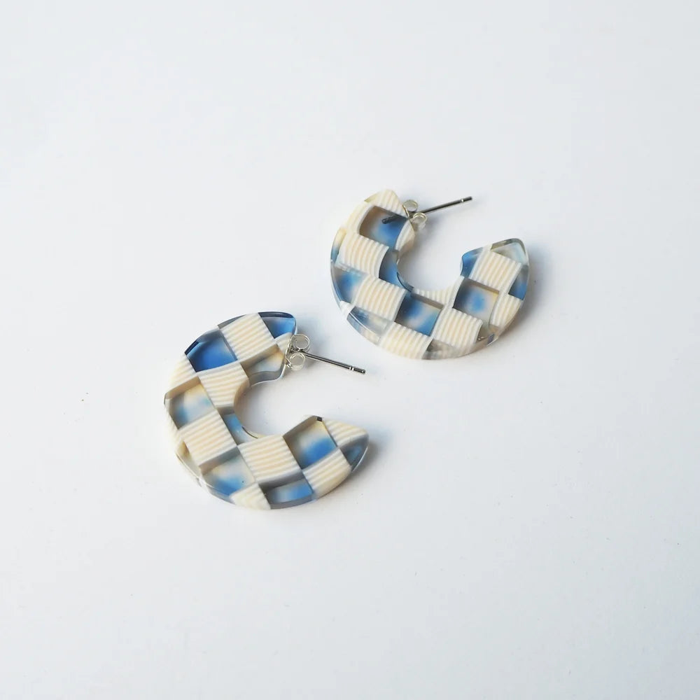 Pair of cream and blue checkered resin hoop earrings.