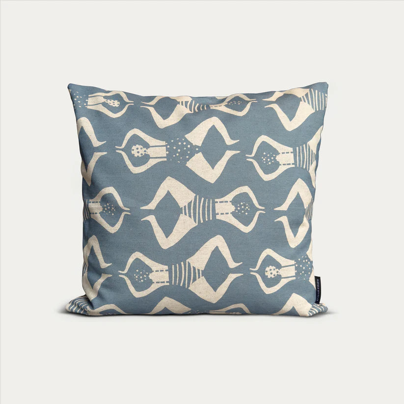 Blue square cushion with a repeating pattern of stylized figures in swimwear.