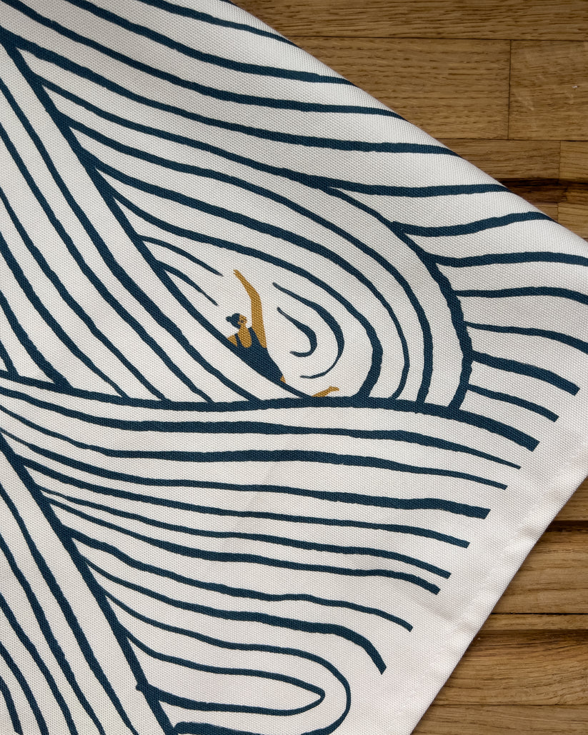 Off-white tea towel with a dark teal wave pattern and a small gold swimmer illustration.