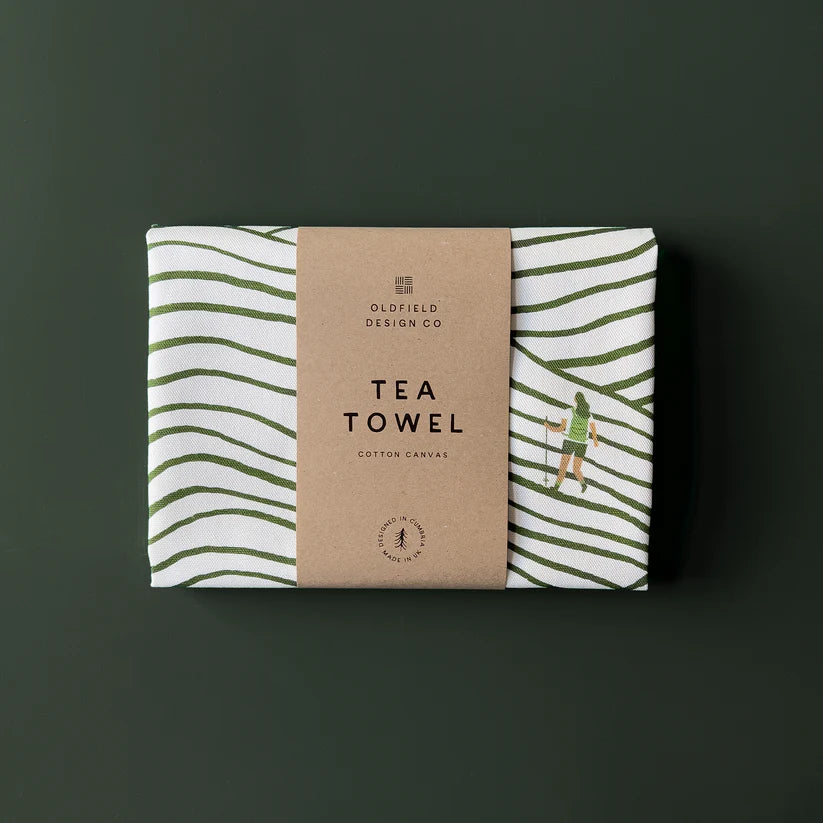 White cotton canvas tea towel with green wavy lines and a small hiker illustration.