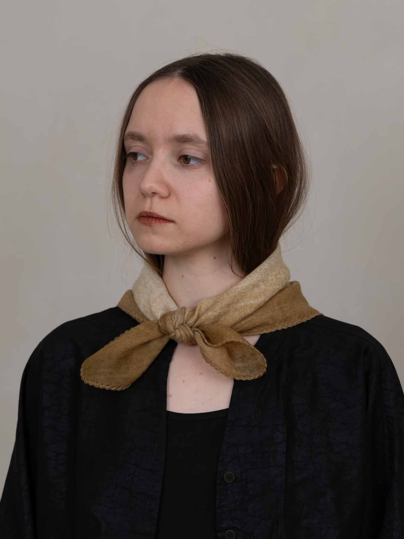 Woman wearing a brown scarf around her neck against a plain background
