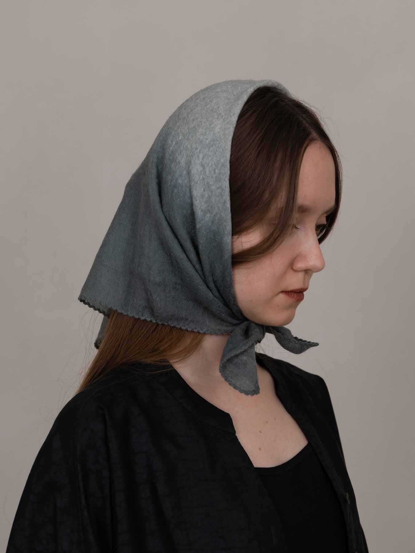 Woman wearing a gray headscarf against a plain background