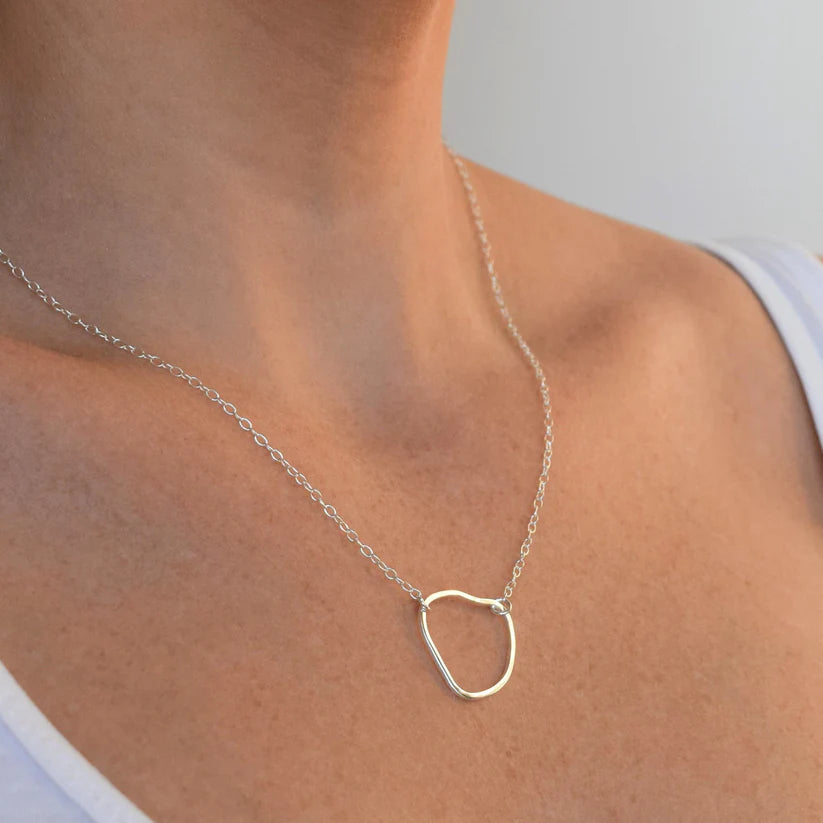 Silver necklace with an irregular, organic-shaped pendant on a delicate chain.