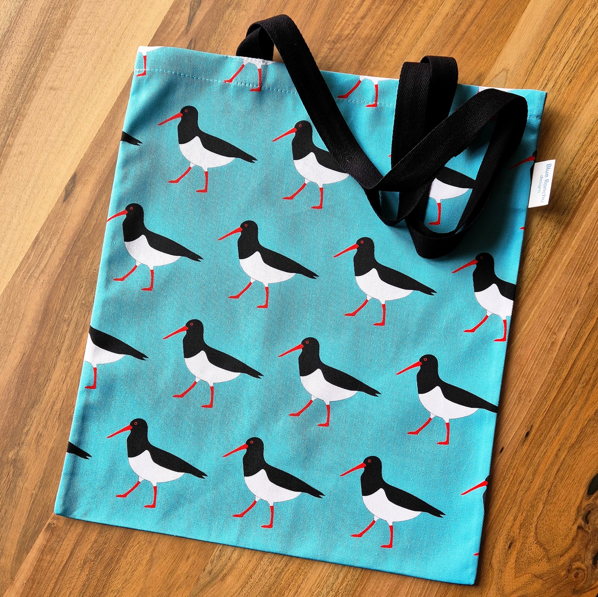Tote bag with bird pattern on a wooden surface